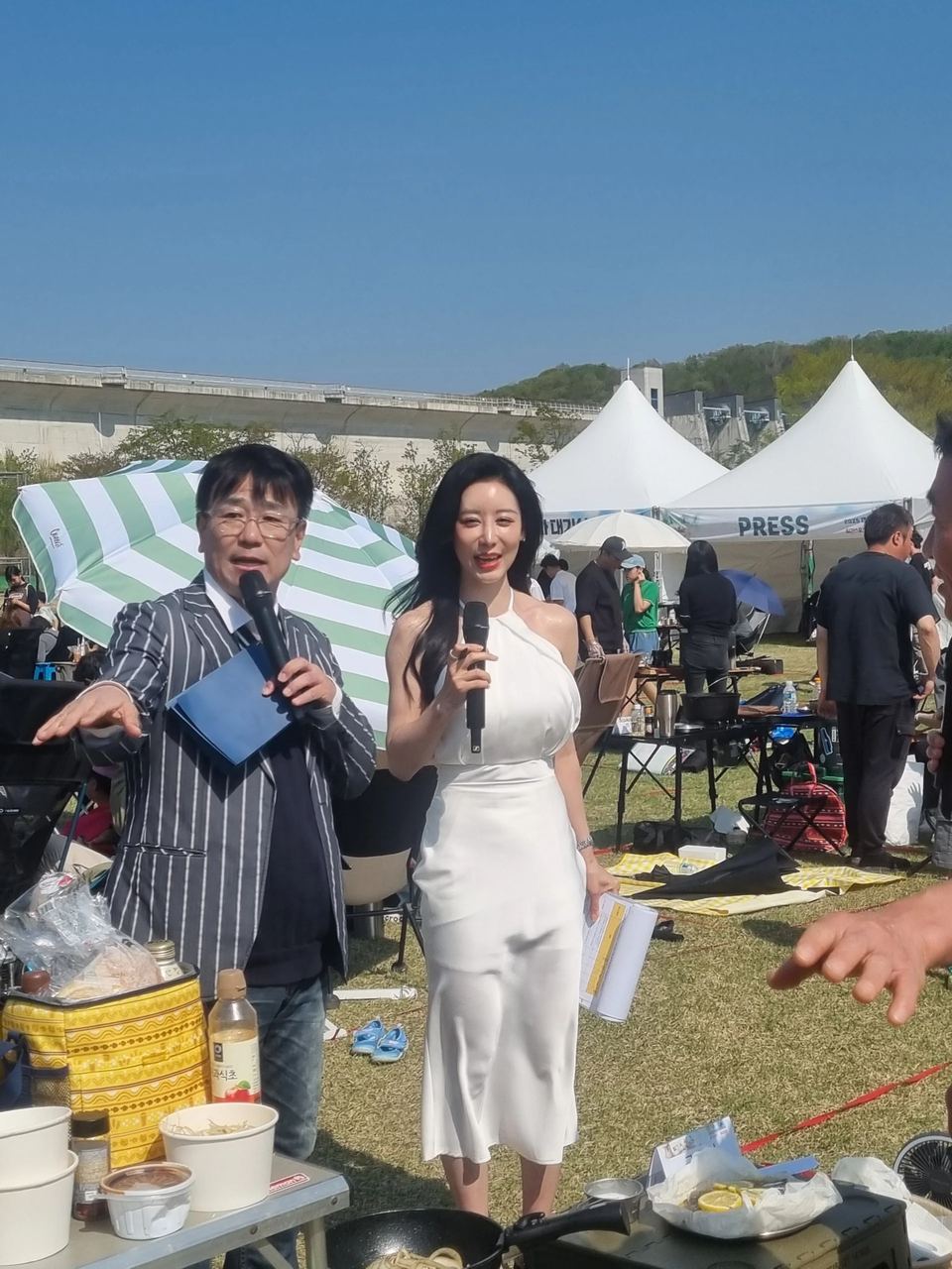 야외 행사장에서 마이크를 든 두 진행자 · 야외 축제 행사