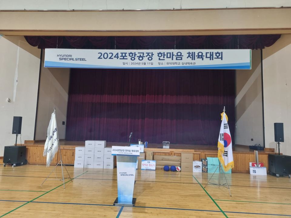 체육대회 무대 앞 연단과 깃발이 놓인 강당 · 체육 행사