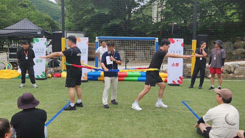 잔디 구장에서 참가자들이 줄다리기 게임을 하는 장면 · 체육 행사