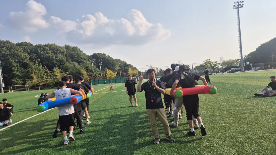 참가자들이 막대 도구를 어깨에 메고 이동하는 게임 · 체육 행사