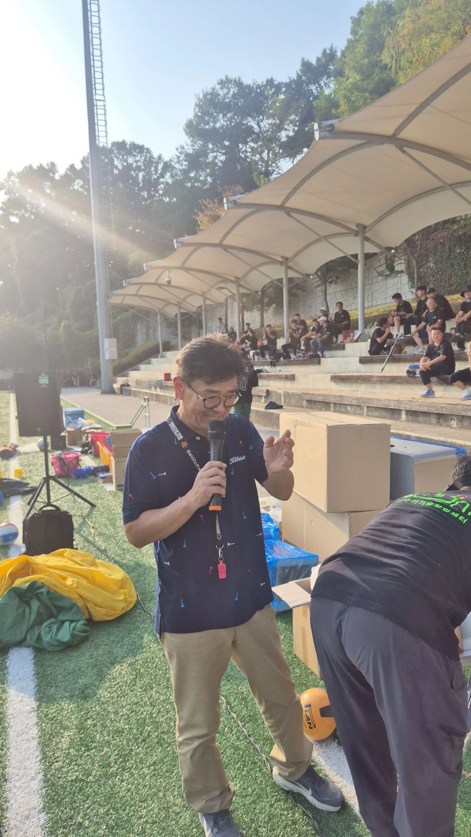 야외 행사장에서 마이크를 들고 말하는 진행자 · 체육 행사