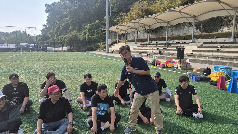 앉은 참가자들 사이에서 마이크로 진행하는 장면 · 체육 행사