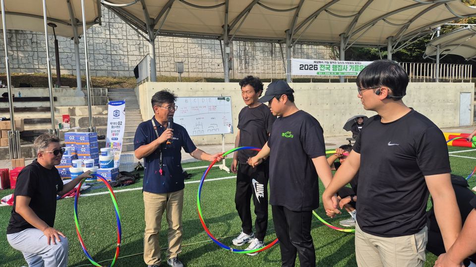 훌라후프를 든 참가자들과 마이크로 진행하는 장면 · 체육 행사