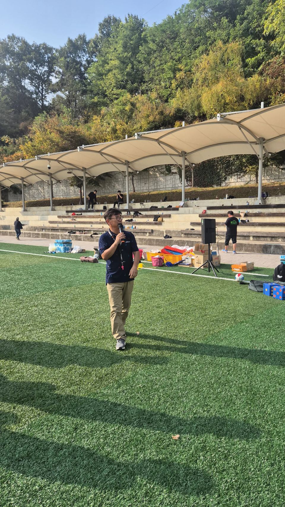 잔디 운동장에서 마이크를 들고 선 진행자 · 체육 행사