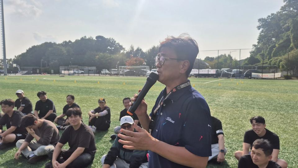 앉은 참가자들 앞에서 마이크로 말하는 진행자 · 체육 행사