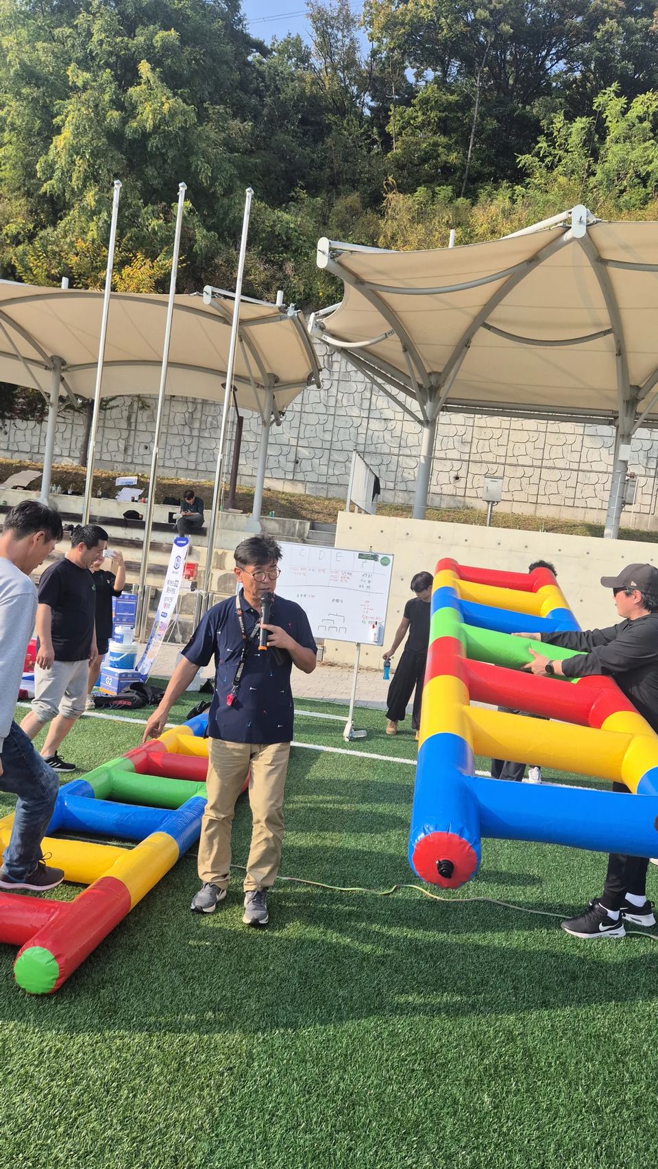막대형 놀이 기구 옆에서 마이크를 든 진행자 · 체육 행사